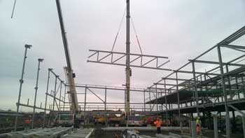 One of the five trusses that form the central zone is lifted into place